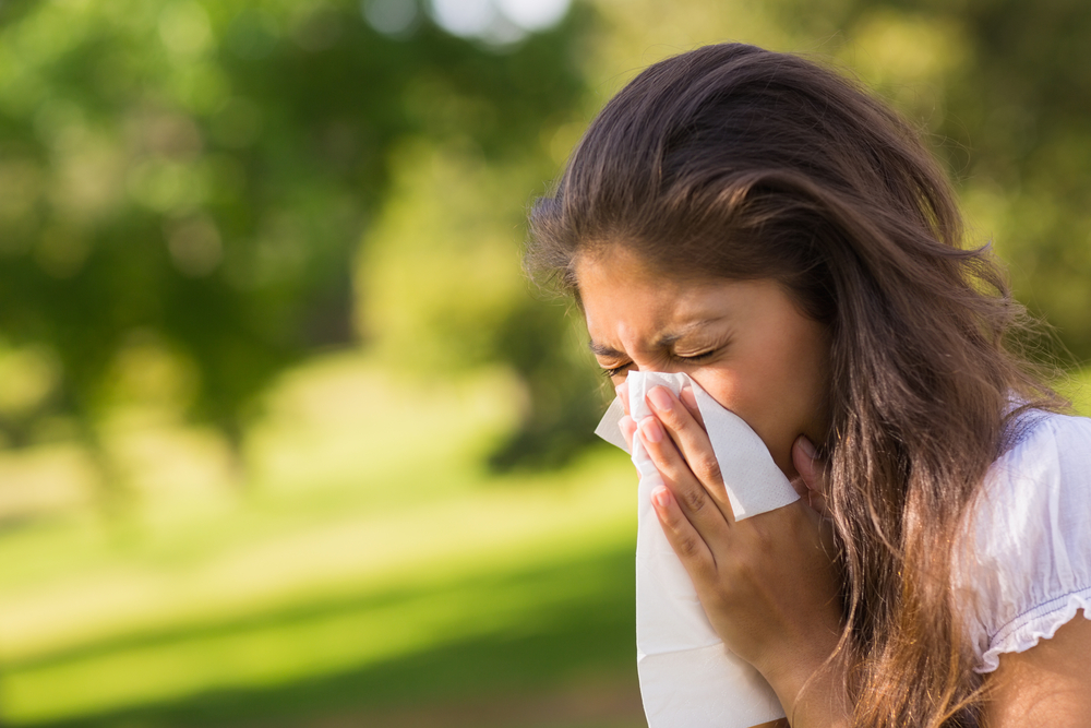 woman outdoors holding a tissue to her face