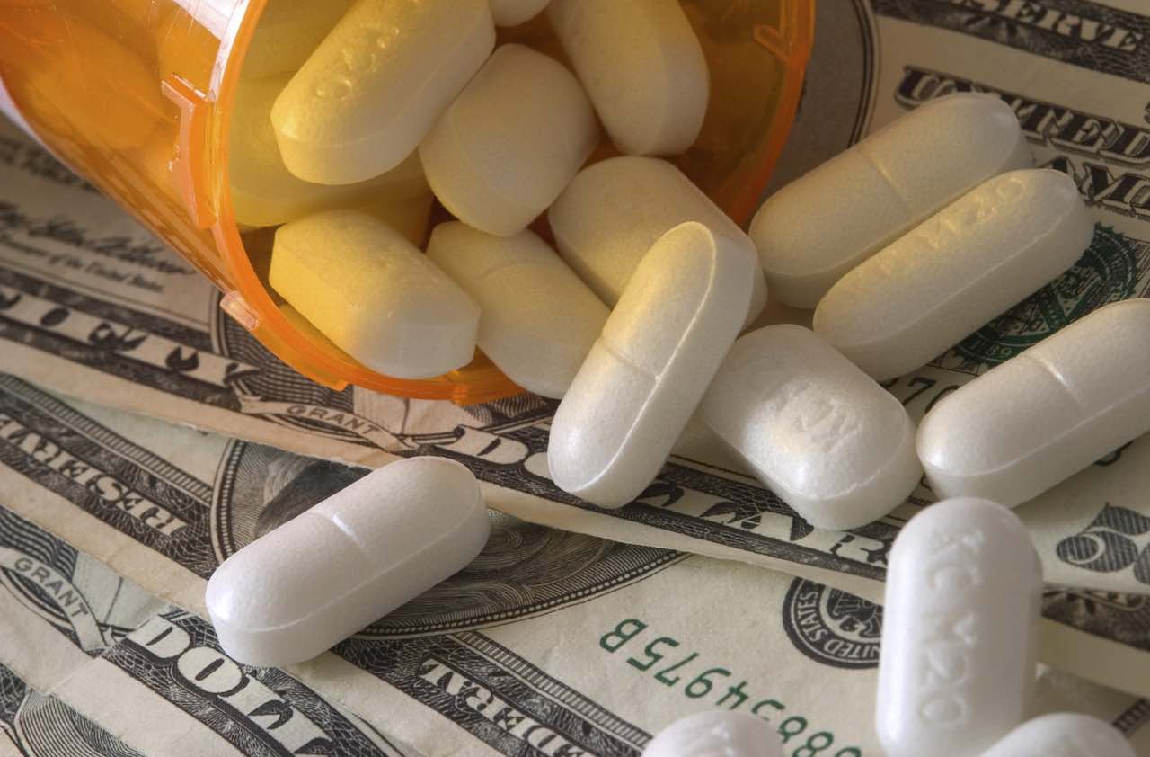 money with a bottle of prescription pills spilling onto it