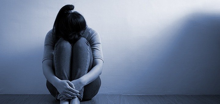 person in a dim room in fetal position