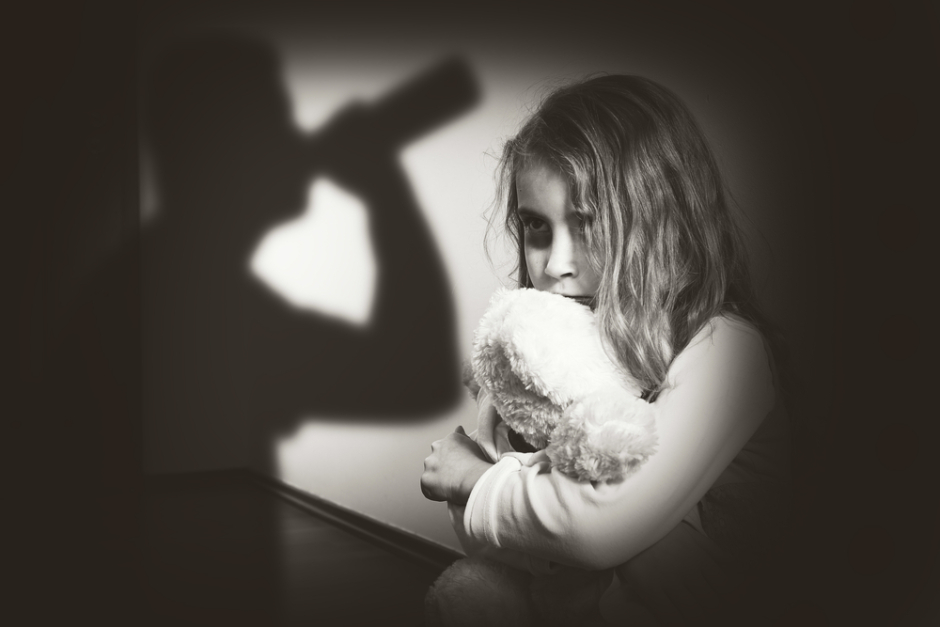 small child in the dark with the shadow of someone drinking alcohol